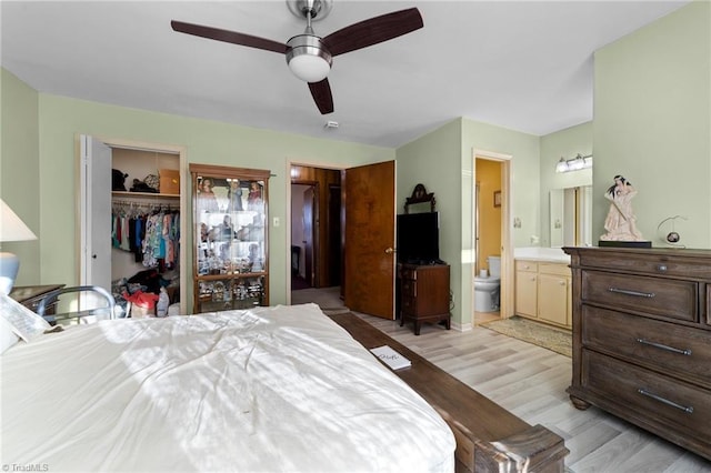 bedroom with a closet, a spacious closet, light wood-style floors, a ceiling fan, and connected bathroom