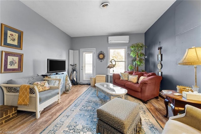 living room with visible vents, wood finished floors, and a wall mounted air conditioner