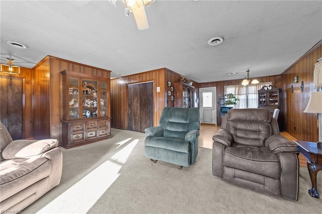 living area with wood walls, carpet, visible vents, and a textured ceiling