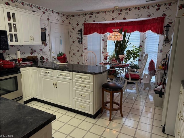 kitchen with stainless steel electric stove, pendant lighting, white cabinetry, light tile patterned floors, and kitchen peninsula