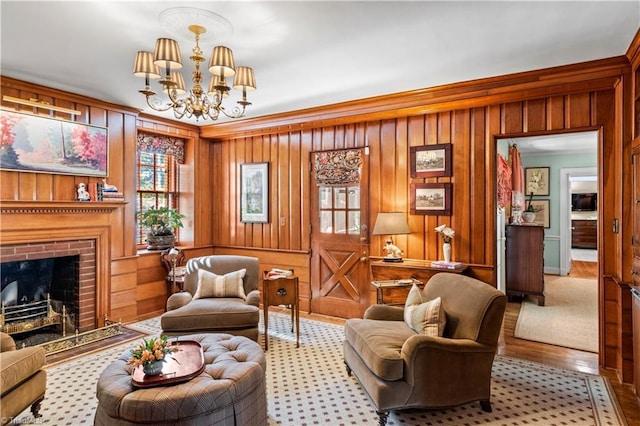living area with a chandelier, ornamental molding, wood walls, a brick fireplace, and wood finished floors