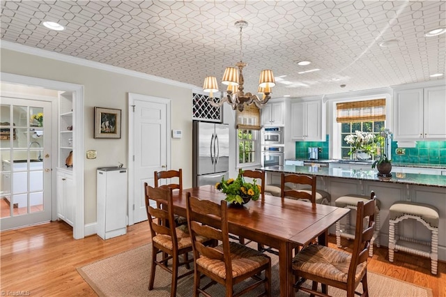 dining room with ornamental molding, a chandelier, light wood-style floors, and recessed lighting