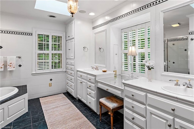 bathroom with a shower stall, ornamental molding, tile walls, two vanities, and a bath