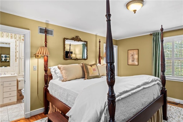 bedroom featuring crown molding, ensuite bath, baseboards, and light wood-style floors