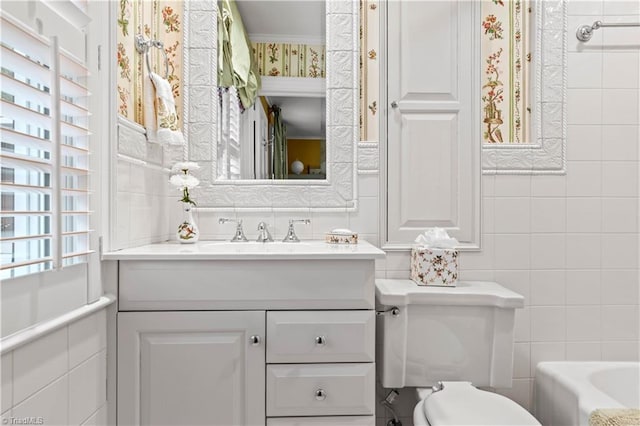 full bathroom with tile walls, toilet, vanity, a tub, and ornamental molding