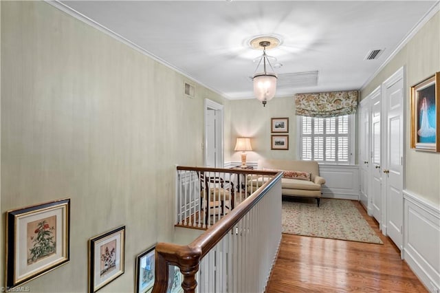 hallway with ornamental molding, light wood-style flooring, and a decorative wall