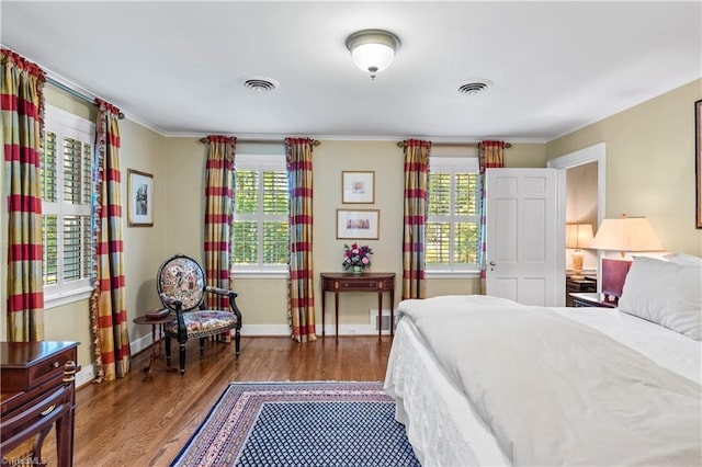 bedroom featuring wood finished floors, multiple windows, baseboards, and ornamental molding
