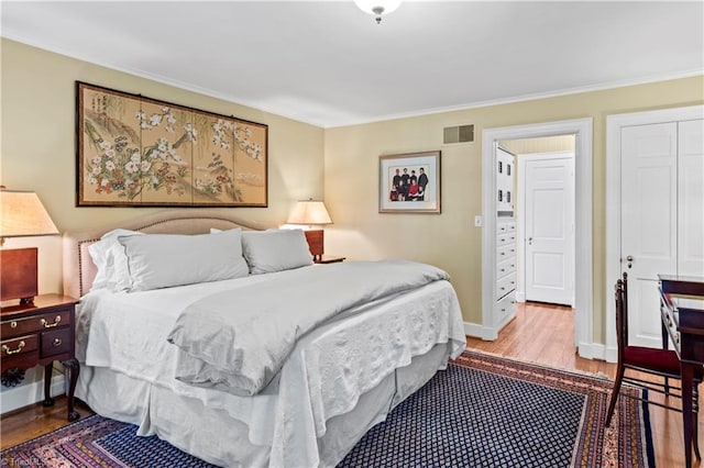 bedroom with wood finished floors, crown molding, and baseboards