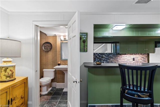bathroom with toilet, ornamental molding, backsplash, and stone finish floors