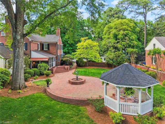 view of grassy yard featuring a gazebo, a patio, and view of wooded area