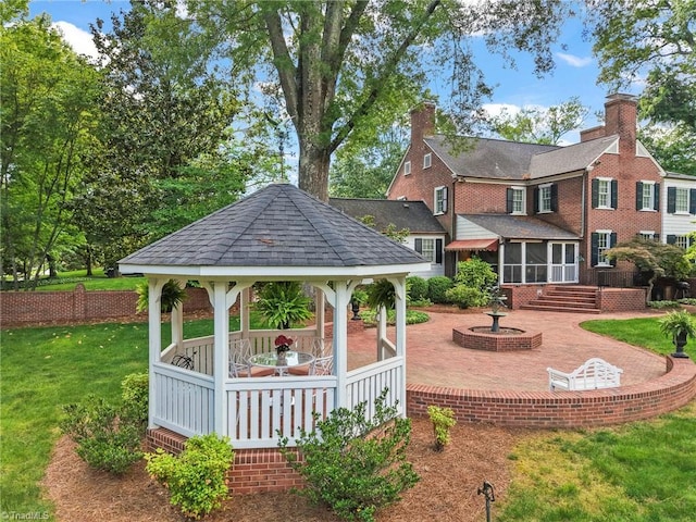 view of green lawn featuring a gazebo, a sunroom, and a patio area