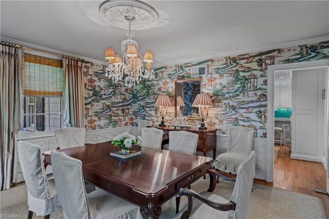 dining room with wallpapered walls, a chandelier, crown molding, wainscoting, and light wood finished floors