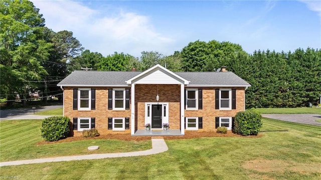 bi-level home featuring a front lawn, a chimney, and brick siding