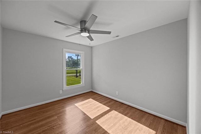 unfurnished room with ceiling fan, baseboards, visible vents, and wood finished floors