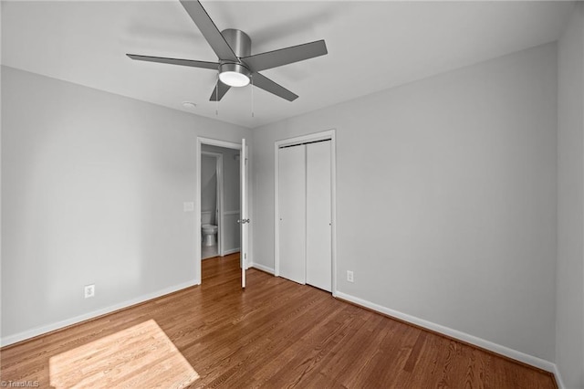 unfurnished bedroom featuring ceiling fan, baseboards, a closet, and wood finished floors