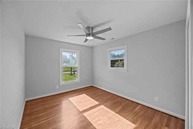 spare room featuring baseboards, ceiling fan, and wood finished floors