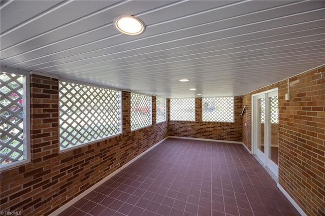 unfurnished sunroom with brick wall