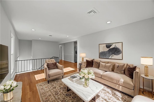 living area featuring recessed lighting, visible vents, and wood finished floors