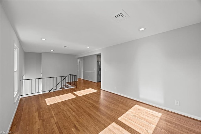 empty room featuring visible vents, wood finished floors, and baseboards