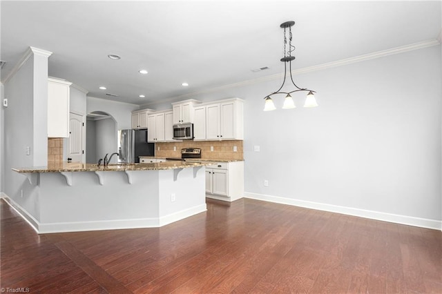 2403 Hammock Dr, High Point, NC 27265 - kitchen featuring stainless steel appliances, a kitchen bar, a peninsula, arched walkways, and crown molding
