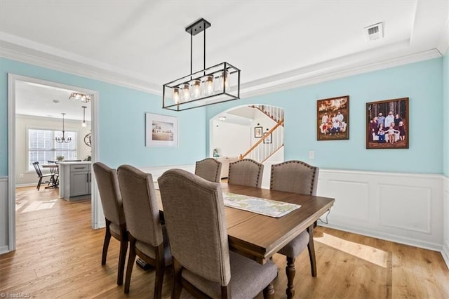 dining area featuring light wood-type flooring, a chandelier, and crown molding