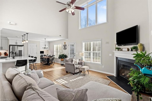 living room with ceiling fan with notable chandelier, light wood-type flooring, and sink