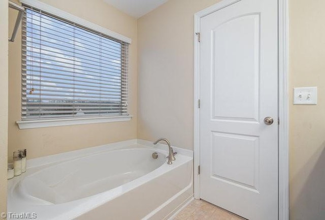 bathroom with tile patterned flooring and a bath