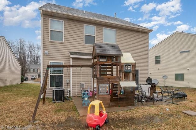 rear view of property featuring a playground, a yard, cooling unit, and a patio area