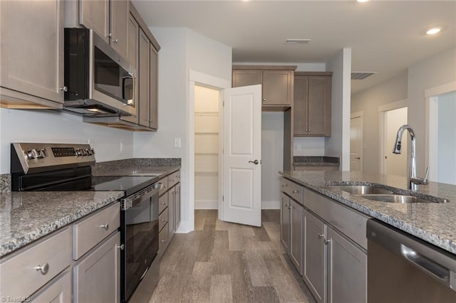 206 Cason Dr, Gibsonville, NC 27249 - kitchen featuring appliances with stainless steel finishes, a sink, wood finished floors, light stone counters, and recessed lighting