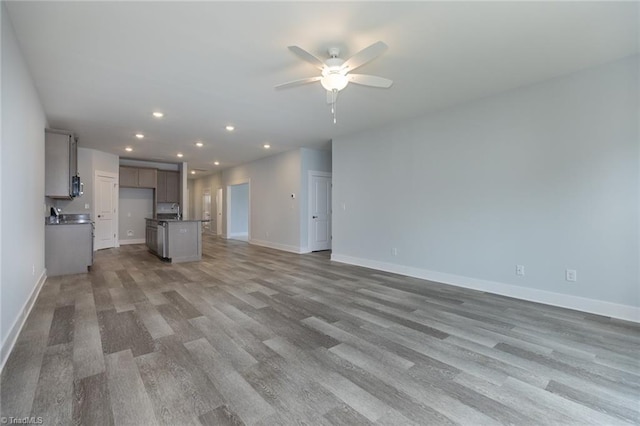 206 Cason Dr, Gibsonville, NC 27249 - unfurnished living room featuring a ceiling fan, baseboards, wood finished floors, recessed lighting, and a sink
