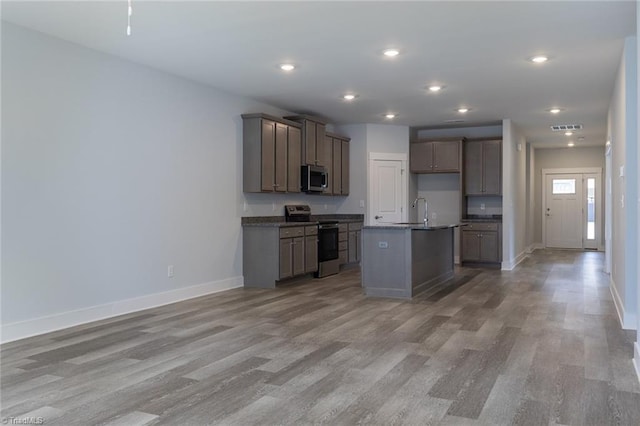 206 Cason Dr, Gibsonville, NC 27249 - kitchen featuring appliances with stainless steel finishes, dark countertops, baseboards, light wood-style floors, and open floor plan