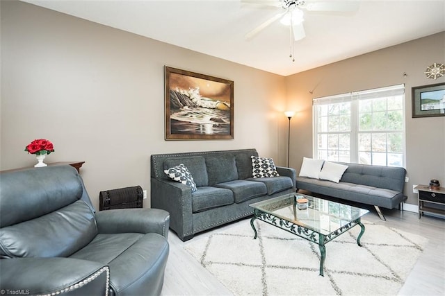 living room featuring ceiling fan, baseboards, and wood finished floors