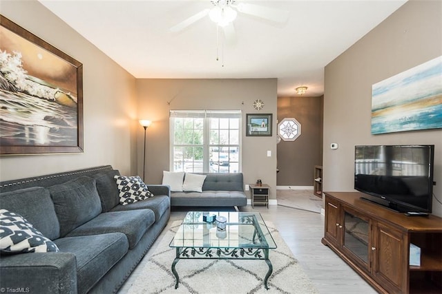 living area with light wood-type flooring, baseboards, and a ceiling fan