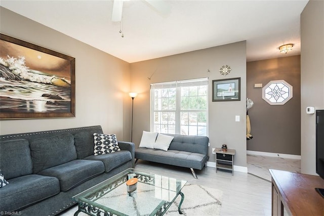 living area with light wood-style floors, a ceiling fan, and baseboards