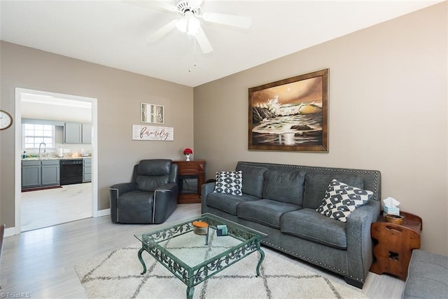 living room with light wood finished floors, baseboards, and a ceiling fan