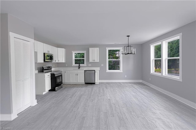 300 Center St, Thomasville, NC 27360 - kitchen featuring appliances with stainless steel finishes, baseboards, light countertops, a sink, and a chandelier
