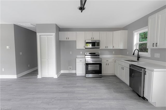 300 Center St, Thomasville, NC 27360 - kitchen featuring stainless steel appliances, a sink, white cabinetry, light wood-style flooring, and light countertops