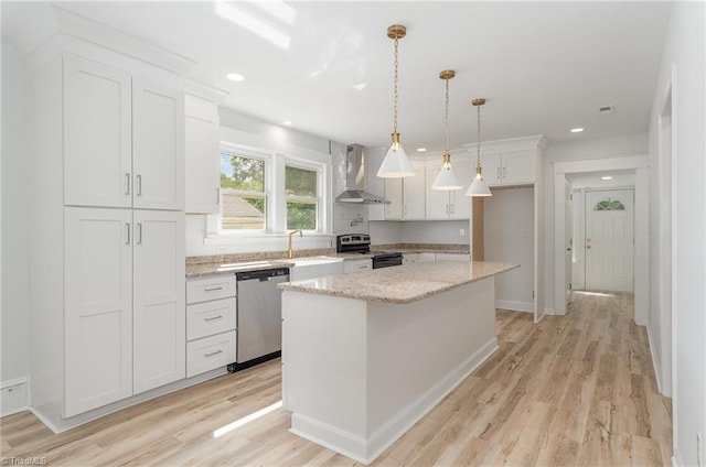 304 Louise Ave, High Point, NC 27262 - kitchen featuring appliances with stainless steel finishes, wall chimney exhaust hood, a sink, white cabinetry, and light wood finished floors
