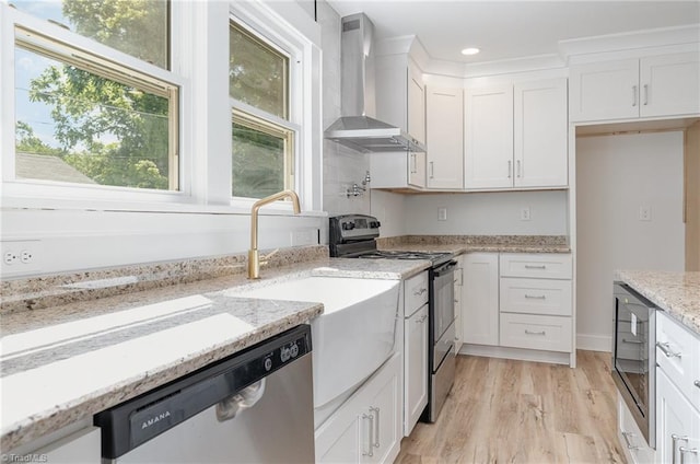 304 Louise Ave, High Point, NC 27262 - kitchen with stainless steel appliances, wall chimney exhaust hood, white cabinetry, light wood finished floors, and light stone countertops
