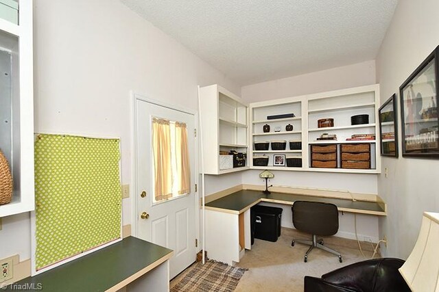 carpeted home office featuring a textured ceiling and built in desk