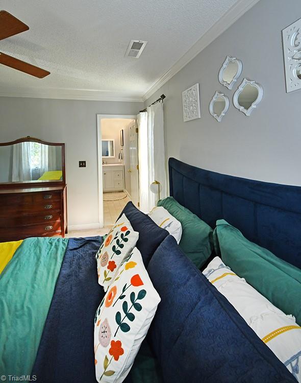 bedroom featuring connected bathroom, crown molding, a textured ceiling, and ceiling fan