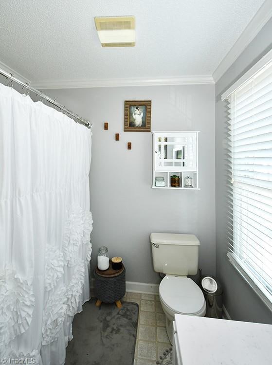 bathroom with vanity, toilet, ornamental molding, and a textured ceiling