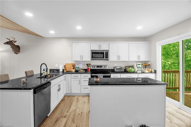kitchen featuring white cabinets, appliances with stainless steel finishes, a sink, and light wood-style floors