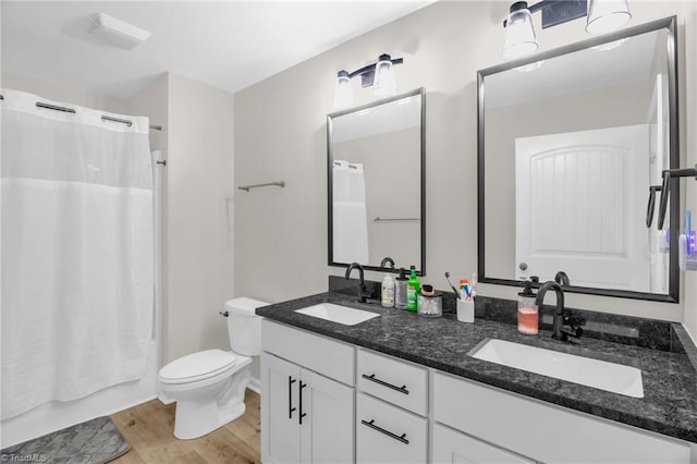 full bath featuring toilet, visible vents, a sink, and wood finished floors
