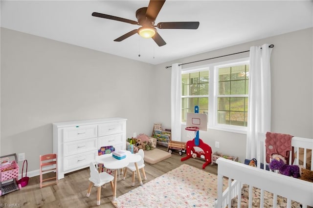 bedroom with light wood-type flooring, a ceiling fan, and baseboards