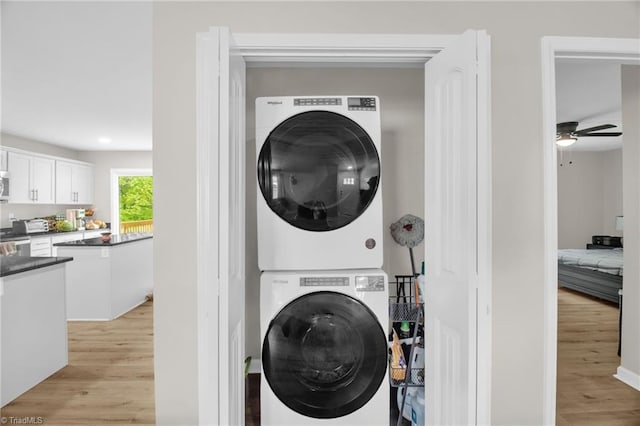 washroom featuring laundry area, stacked washing maching and dryer, ceiling fan, and light wood-type flooring