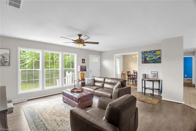 living area with baseboards, ceiling fan, wood finished floors, and visible vents