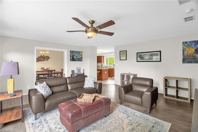 living area with visible vents, baseboards, ceiling fan with notable chandelier, and wood finished floors