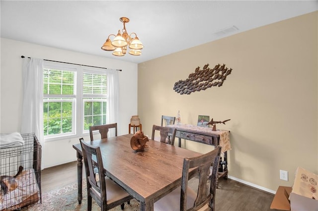 dining area featuring baseboards, a chandelier, wood finished floors, and visible vents