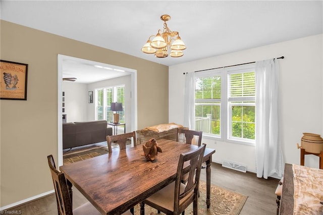 dining room with an inviting chandelier, baseboards, wood finished floors, and visible vents